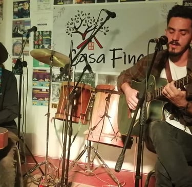 Dos músicos interpretan una sesión acústica en vivo con una guitarra y un tambor de mano en Casa Fin
