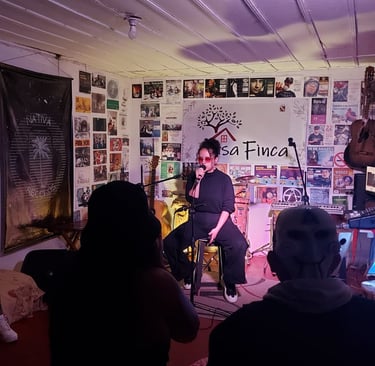 Una cantante se presenta en vivo sobre un pequeño escenario en un espacio musical íntimo