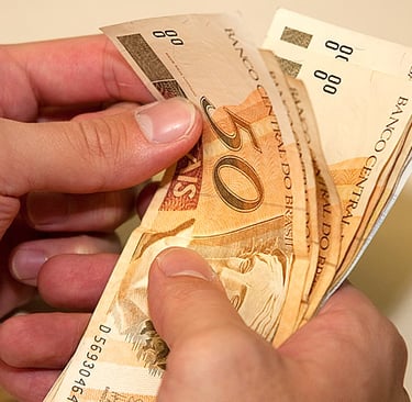 Pessoa contando notas de 50 rais