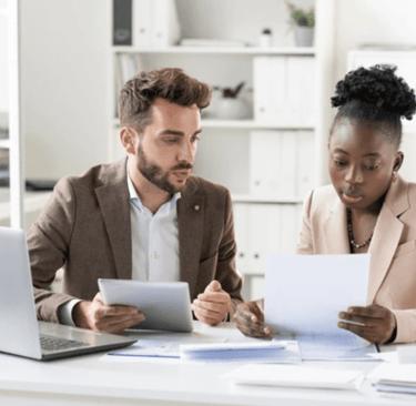 White male at a desk with a Black female looking over some paperwork