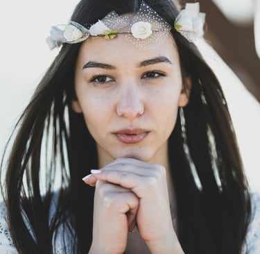 Portrait of a young woman wearing a white flower crown and lace dress for a boho style wedding photoshoot.