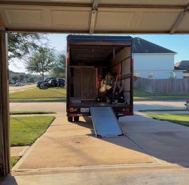 Professional moving truck with ramp parked in a driveway, loaded with furniture for residential relocation.