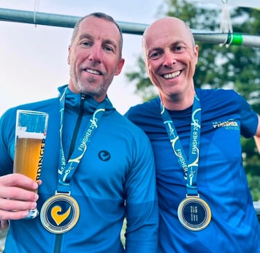 James Oswald Coaching Doug Jones celebrating with Challenge Roth finisher medals and an Erdinger.