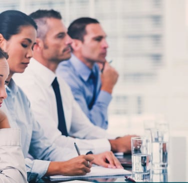Bored business professionals attending a corporate meeting in a modern office boardroom.