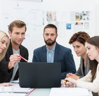 Diverse business team collaborating on a project during a corporate office meeting with a laptop.