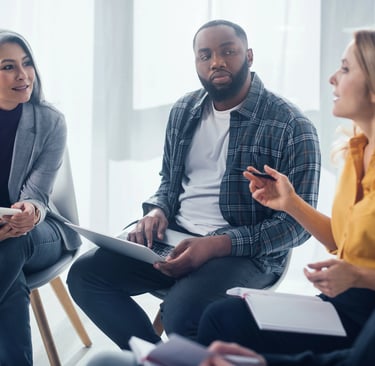 Diverse business team collaborating in a professional office meeting with laptops and notebooks.