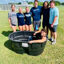 a group of people standing around a large black plastic tub