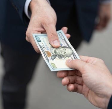A close-up of hands exchanging money with a warm background of a restaurant.