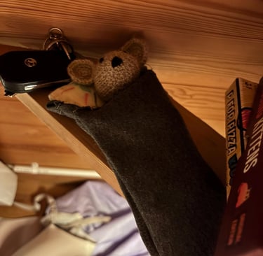 a little crocheted mouse is hanging from a shelf