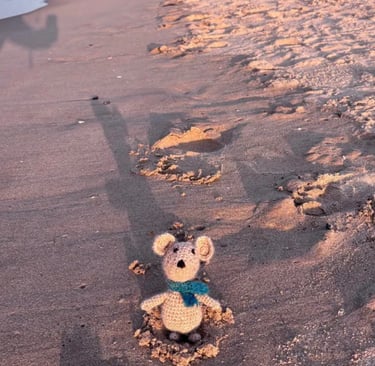 a small crocheted mouse sitting on a beach