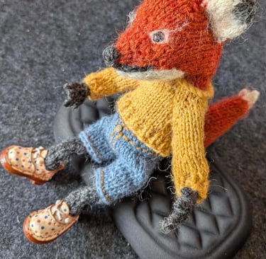 a small knitted fox sitting on top of a black shoe