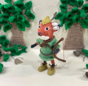 a little knitted fox dressed as Robin Hood from Disney in the woods