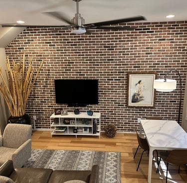 Modern living room featuring a rustic thin brick accent wall, wall-mounted TV, and hardwood floors.