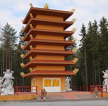 A seven-story orange Buddhist pagoda with gold accents and stone statues in a forest setting.