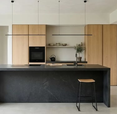 Cucina minimalista con isola in pietra scura, mobili in legno chiaro e linee essenziali