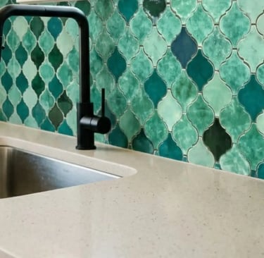 Dettaglio cucina con lavello integrato, rubinetteria nera e rivestimento in zellige verdi smaltate