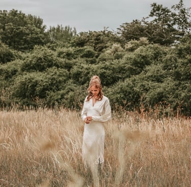 a woman in a white dress standing in a field