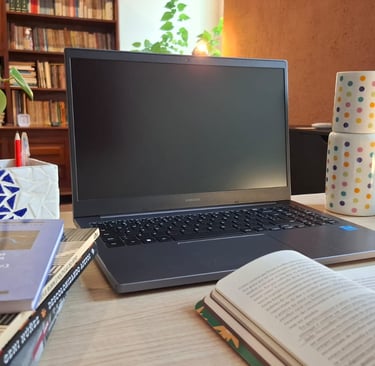 Mesa de trabalho com livros de autoras como Ana Suy, Gayle Rubin e Geni Núñez, ao lado do notebook u