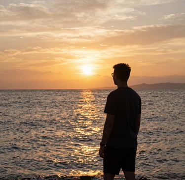 A sunny beach scene with a person wearing light summer surfwear from the collection