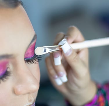Maquilladora profesional que aplica sombras de ojos con brillo rosa vibrante con un pincel