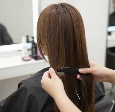 A stylist gently applying hair color in a calm, luxurious salon setting.