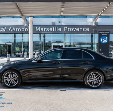 Black Mercedes sedan parked at Marseille Provence Airport for private cruise excursion transfer.