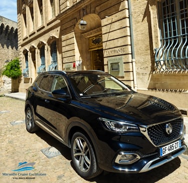 Black MG SUV parked on a cobblestone street in front of La Mirande Hotel in Avignon, France.