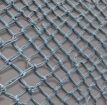 Photo of factory workers inspecting rolls of harmonika wire during production.