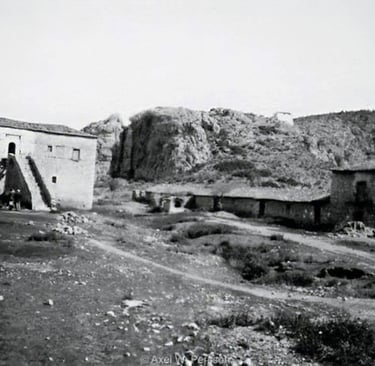 Vintage black and white photo of historic stone buildings and a rocky hillside at Kandia