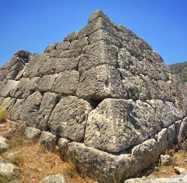 The ancient stone Pyramid of Hellinikon in Greece made of large limestone blocks under a clear blue sky.