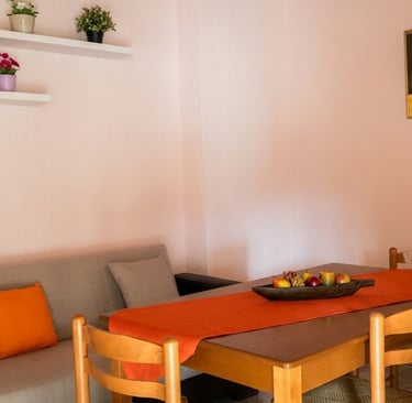 Modern dining room with a wooden table, orange runner, grey sofa, and minimalist wall shelves.