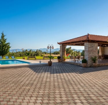 Luxury outdoor patio with swimming pool, stone pavilion, and mountain views.