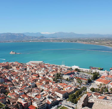Aerial view of Nafplio city in Greece featuring red roofs, turquoise Argolic Gulf, and Bourtzi castle.