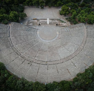 Aerial view of the ancient Theatre of Epidaurus in Greece surrounded by lush green trees.