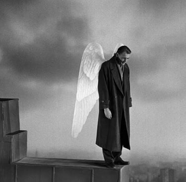A melancholic angel with white wings stands on a rooftop ledge overlooking Berlin in a black and white film still.