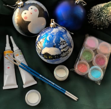 Hand-painted blue Christmas ornaments with brushes, glitter, and craft paint for DIY holiday decorating.