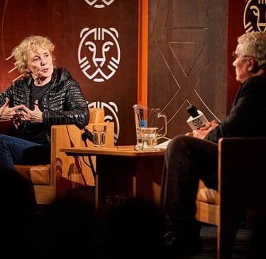 French director Claire Denis speaking at a film festival stage interview with a moderator.