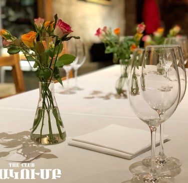 Elegant restaurant table setting with fresh rose flower centerpieces and crystal wine glasses.