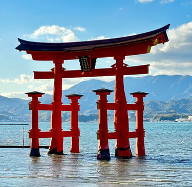 The floating Itsukushima Shrine Torii gate in Miyajima, Japan, standing in water with scenic mountains.