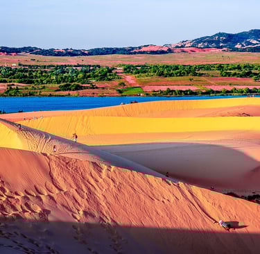 Wide landscape shot of Sand Dunes in Mui Ne Vietnam at sunrise with tiny tourists walking on t