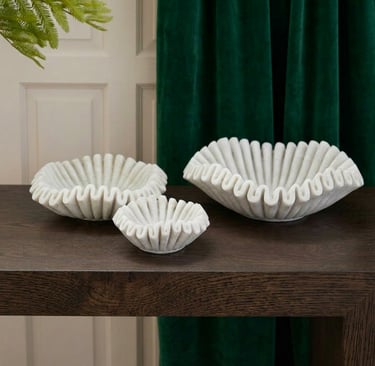 Handcrafted white marble bowls styled on dark oak table with deep green velvet curtains in a luxurious organic interior