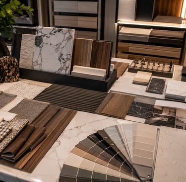 Interior design mood board featuring marble tiles, wood veneers, fabric swatches, and a paint color fan deck.