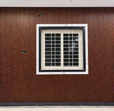 Modern interior wall featuring dark wood fluted panels and a window with a decorative marble frame.