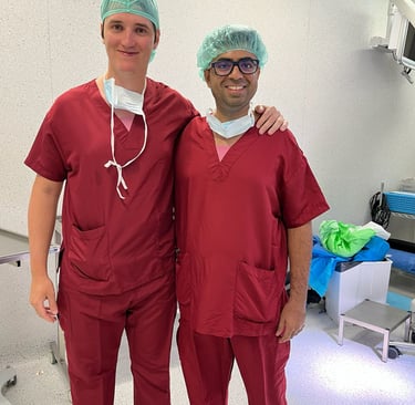Two smiling male surgeons in red medical scrubs and hairnets dr piyush vasaikar dhule