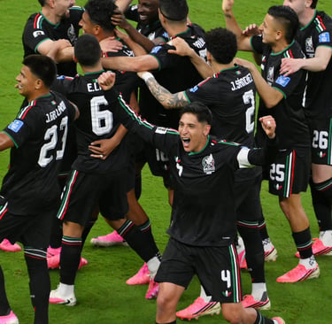Mexico national football team players celebrating a goal on the field in black jerseys.