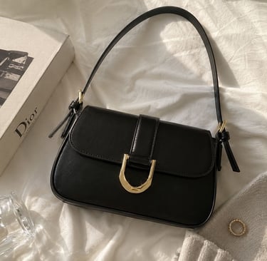 Black shoulder bag with gold buckle detail on a beige luxury background.
