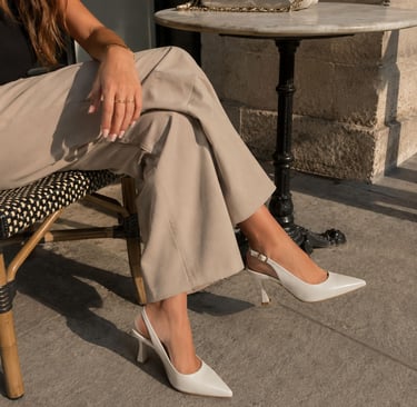 Woman wearing white pointed toe slingback heels.