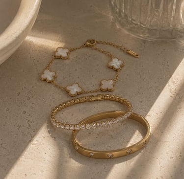 Minimalist gold bracelets with clover detail.