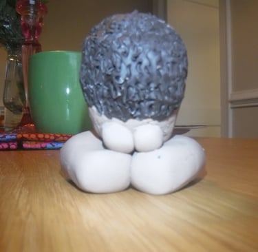 Handcrafted clay sculpture of a person kneeling in prayer or meditation on a wooden table.