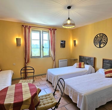 chambre Ocre de "la ramade" avec 2 lits séparés, une table et miroir rond, mur ton jaune ocre.